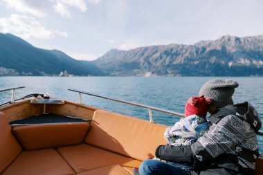 Anne kucağında küçük bir çocukla denizde bir teknede yüzüyor ve dağlara bakıyor. Arkadan bak. Yüksek kalite fotoğraf