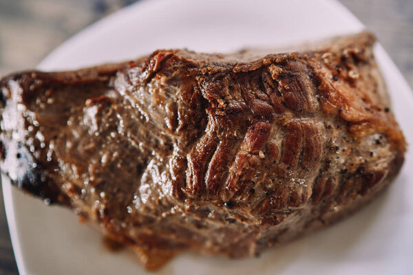 Roast beef with spices with a baked crust lies on a plate on a table. High quality photo