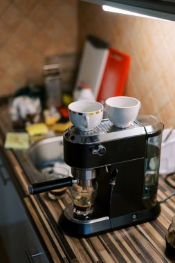 Keçiboynuzu kahve makinesinin üzerinde kahve standı olan fincanlar masanın üzerinde kahve hazırlıyor. Yüksek kalite fotoğraf
