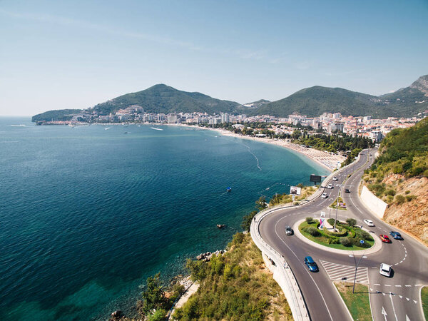 Highway with a circular turn over the sea at the foot of the mountains. Budva, Montenegro. Drone. High quality photo
