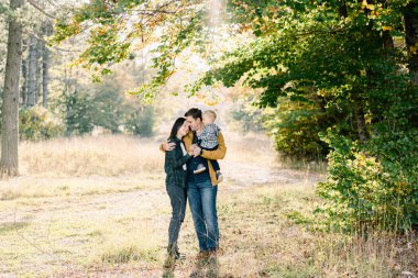 Annem, parkta dururken başını babamın kollarında küçük bir kızla omzuna koydu. Yüksek kalite fotoğraf