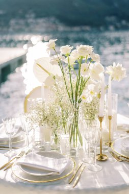 Deniz kıyısındaki iskelede servis edilen bir masada beyaz çiçekler duruyor. Yüksek kalite fotoğraf