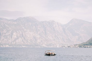 Keşif teknesi açık bir sis bulutuyla bir dağ sırasının arka planına karşı denizde yol alır. Yüksek kalite fotoğraf