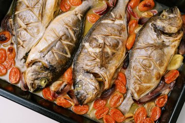 Sebzelerle pişirilmiş Dorado, masada bir yemek tepsisinin üzerinde yatıyor. Yüksek kalite fotoğraf