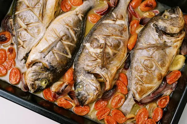 Dorado baked with vegetables lies on a baking sheet on the table. High quality photo