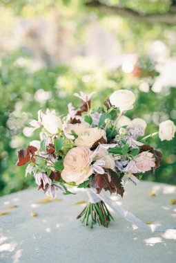 Renkli düğün buketi yeşil bir bahçede taş bir kaide üzerinde duruyor. Yüksek kalite fotoğraf