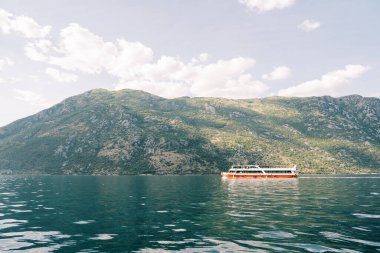 Renkli çift katlı keşif gemisi yüksek bir dağ sırtı boyunca mavi denizde yelken açar. Yüksek kalite fotoğraf