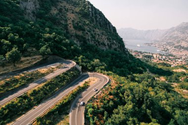 Arabalar Kotor Körfezi 'nin yukarısındaki yeşil dağlarda yılan yolu boyunca ilerliyorlar. Karadağ. Yüksek kalite fotoğraf