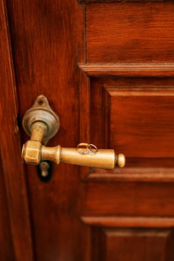 Alyanslar antik, ahşap, kahverengi bir kapının bronz sapında duruyor. Yüksek kalite fotoğraf