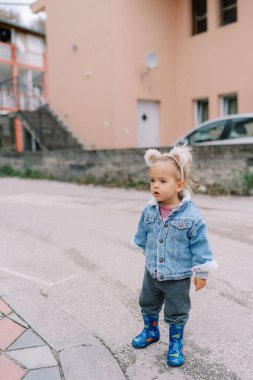 Küçük kız evin avlusunda duruyor ve uzaklığa bakıyor. Yüksek kalite fotoğraf