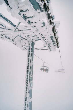 Dört koltuklu asansörün karla kaplı sütununda hareket eden sandalyeler. Yüksek kalite fotoğraf