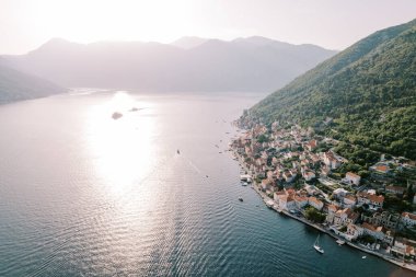 Perast sahilinin açıklarında, dağların arasında güneş ışıldıyor. Karadağ. Drone. Yüksek kalite fotoğraf