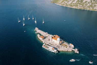 Kotor Körfezi 'ndeki Kayalıklar Leydisi Kilisesi' nin etrafı demirli tekneler ve bir gemiyle çevrili. Karadağ. Drone. Yüksek kalite fotoğraf