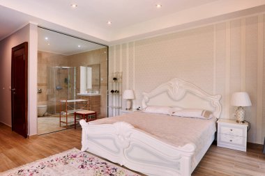 Cam duvarın arkasında duş odası olan komodinli çift kişilik yatak. Yüksek kalite fotoğraf