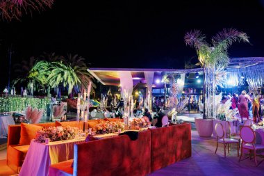 Açık terastaki kanepelerin yanında gece aydınlatmalı şenlik masaları. Yüksek kalite fotoğraf