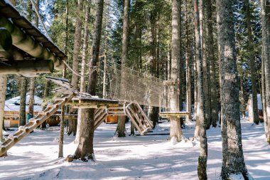 Karlı kozalaklı bir ormanda, ahşap evlerle dolu bir macera parkı. Yüksek kalite fotoğraf