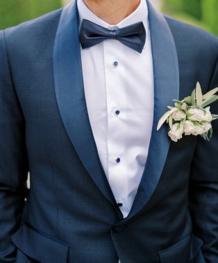 Yaka çiçekli koyu mavi takım elbiseli damat elleri pantolonunun cebinde duruyor. Kırpılmış. Yüzsüz. Yüksek kalite fotoğraf