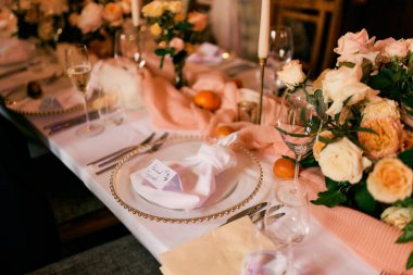 Davetiye, şenlik masasındaki çiçek buketlerinin yanındaki bir tabakta bir peçetenin üzerinde duruyor. Yüksek kalite fotoğraf