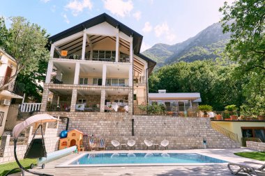 Teraslı büyük bir malikane ve dağların eteklerinde yeşil ağaçlarla çevrili bir yüzme havuzu. Yüksek kalite fotoğraf