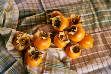 Olgun hurma, masanın üzerindeki eğilmiş masa örtüsünün üzerinde yatıyor. Üst Manzara. Yüksek kalite fotoğraf