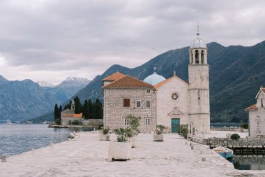 Kayalıklardaki Meryem Ana Kilisesi. Kotor Körfezi 'ndeki bir adada. Arkasında dağlar var. Karadağ. Yüksek kalite fotoğraf