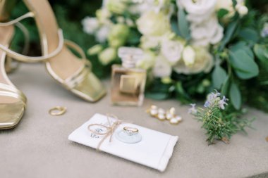 Evlilik yüzüğü, gelin ayakkabısının yanında bir iplikle mühürlenmiş bir davetiyede yatıyor. Yüksek kalite fotoğraf