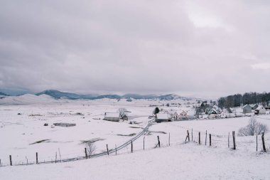 Dağ vadisindeki ormanın kıyısındaki bir köyde karlı bir yol. Yüksek kalite fotoğraf