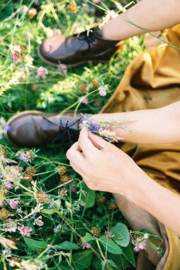 Anne elleri küçük kızın ayaklarındaki ayakkabılara kır çiçekleri yerleştirir. Kırpılmış. Yüksek kalite fotoğraf