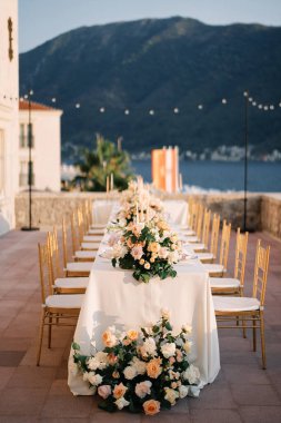 Renkli çiçek buketleri deniz kıyısındaki eski bir evin terasında uzun bir şenlik masasının üzerinde duruyor. Yüksek kalite fotoğraf