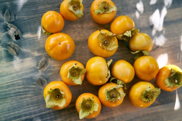 Sulu hurmalar güneş ışığı altında ahşap bir masanın üzerinde toplu halde yatarlar. Üst Manzara. Yüksek kalite fotoğraf