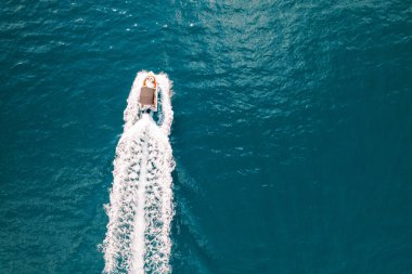 Sürat teknesi turkuaz bir denizde yol alır, arkasında beyaz köpüklü bir iz bırakır. Üst Manzara. Yüksek kalite fotoğraf