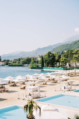 Kumsalda yüzme havuzları, güneş pansiyonları ve deniz kenarında güneş şemsiyeleri var. Yüksek kalite fotoğraf