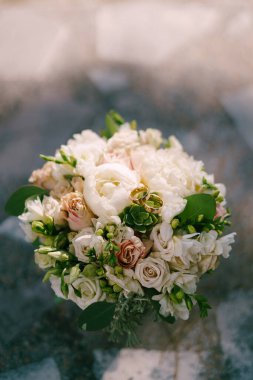 Bir çift alyans gelin buketinin üzerinde duruyor. Yüksek kalite fotoğraf