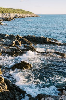 Köpüren deniz dalgaları sahil kayalıklarını yıkıyor. Yüksek kalite fotoğraf