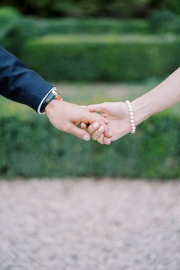 Gelin, damadın elini parkta tutuyor. Kırpılmış. Yüzsüz. Yüksek kalite fotoğraf
