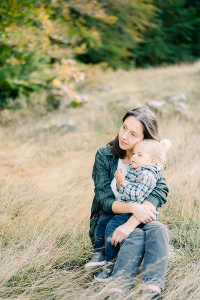Annem kucağında oturan küçük bir kıza sarılıyor ve uzaklığa bakıyor. Yüksek kalite fotoğraf
