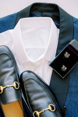 Siyah erkek ayakkabıları mavi bir takım elbisenin üzerinde bir kutunun içindeki kol düğmelerinin yanında duruyor. Yüksek kalite fotoğraf