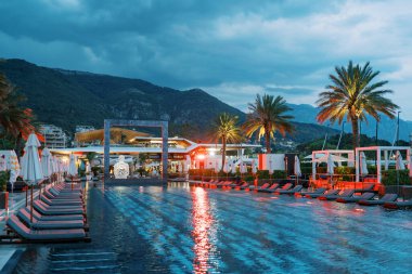 Kare kemerli uzun havuzun yanındaki kırmızı ışık ve dağların eteklerinde güneşlik. Porto, Karadağ. Yüksek kalite fotoğraf