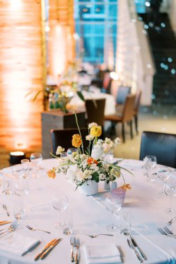 Çatal bıçak seti setin üzerindeki katlanmış peçetelerin yanında renkli bir buket çiçekle yatar. Yüksek kalite fotoğraf