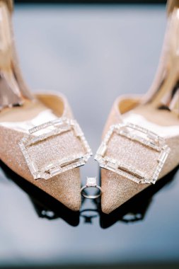 Nişan yüzüğü gelinin ayak parmaklarının arasında duruyor altın topuklu ayakkabılar. Yüksek kalite fotoğraf