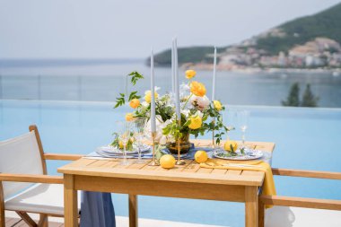 Parlak çiçekli iki kişilik şenlik masası havuzun kıyısında duruyor. Yüksek kalite fotoğraf