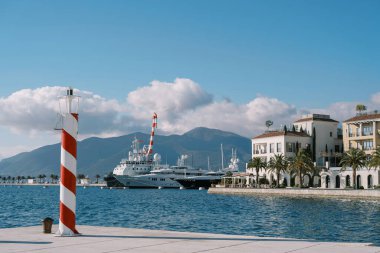 Lüks bir marinanın iskelesinde demirli yatları olan küçük çizgili deniz feneri duruyor. Yüksek kalite fotoğraf