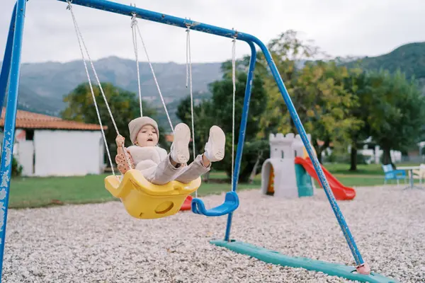 Küçük kız yeşil bir parkta salıncakta sallanıyor. Yüksek kalite fotoğraf