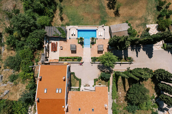 Ancient villa with a swimming pool in a green garden and sun loungers. Drone. High quality photo