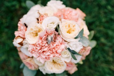 Alyanslar yeşil çimlerin üzerinde duran gelin buketinin üzerinde duruyor. Yüksek kalite fotoğraf