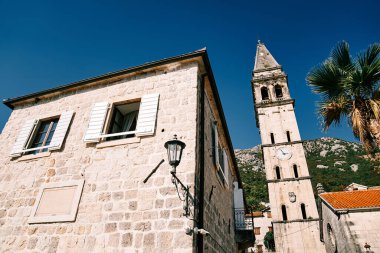 Aziz Niklas Kilisesi 'nin yüksek çan kulesindeki saat eski evlerin arasında. Perast, Karadağ. Yüksek kalite fotoğraf