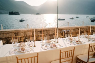 Şamdanlı uzun festival masası deniz kıyısındaki terasta duruyor. Yüksek kalite fotoğraf