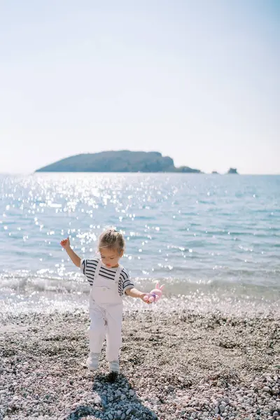 Gadis Kecil Dengan Mainan Berjalan Sepanjang Pantai Kerikil Menyeimbangkan Dengan — Stok Foto