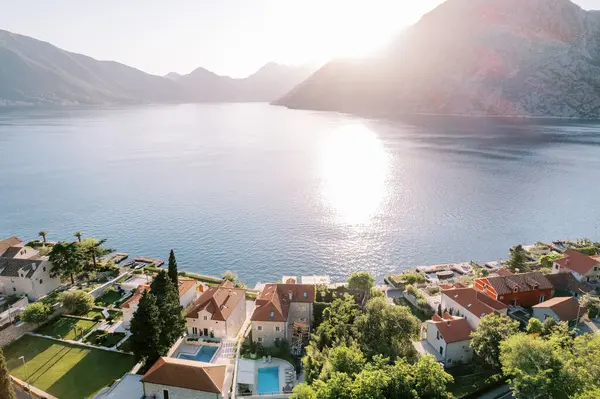 Kotor Körfezi kıyılarında kırmızı çatıları olan eski evlerin avlularında yüzme havuzları. Orahovac, Karadağ. Drone. Yüksek kalite fotoğraf