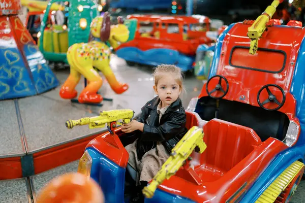 Mała Dziewczynka Siedzi Zabawkowym Samochodzie Karuzeli Trzymając Kierownicę Wysokiej Jakości — Zdjęcie stockowe